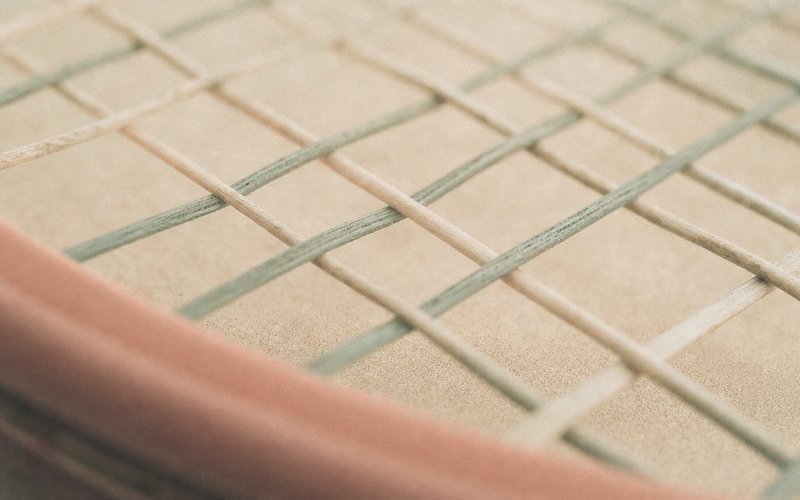 Nahaufnahme eines Tennisschläger-Saitenbetts in weichem Pastelllicht